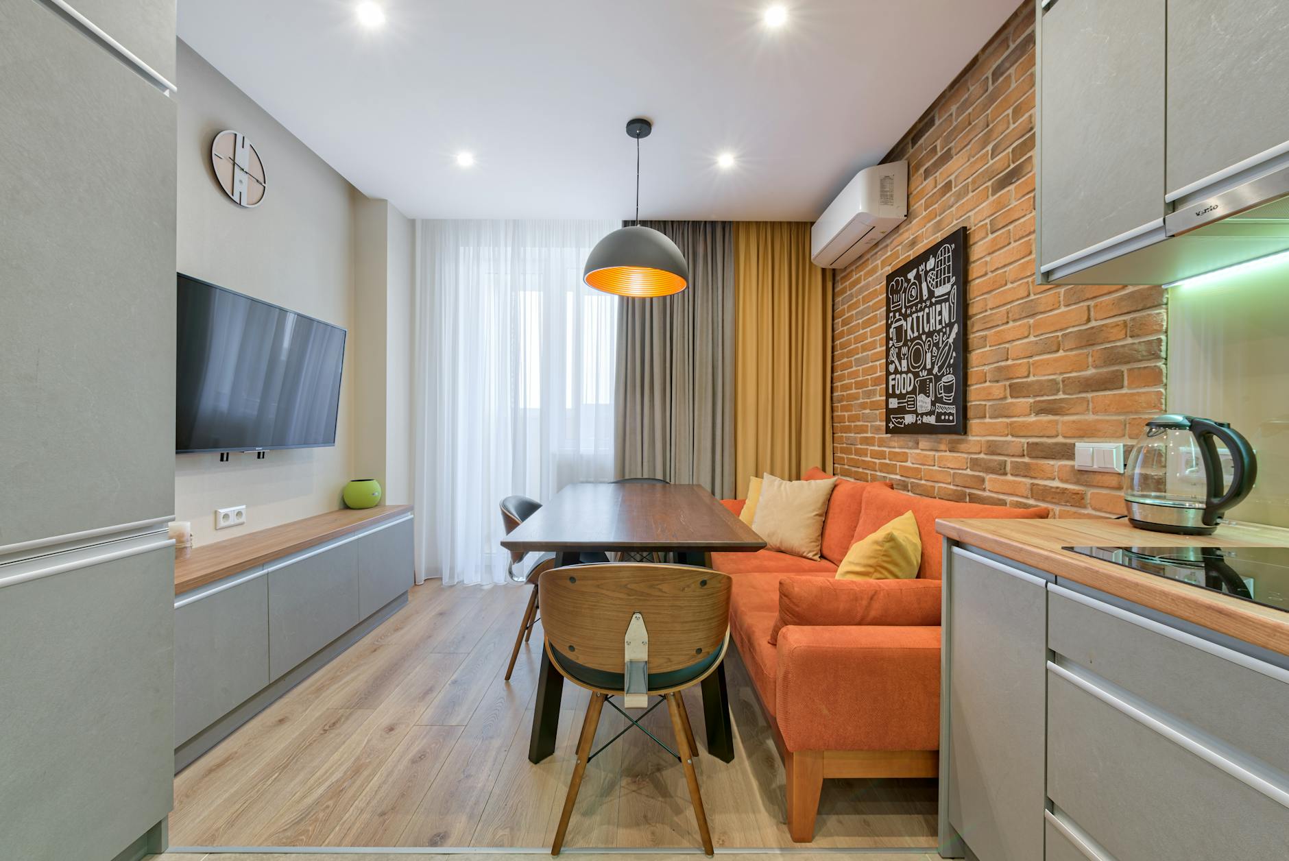 Nowoczesny salon z ceglaną ścianą, pomarańczową sofą i drewnianymi meblami