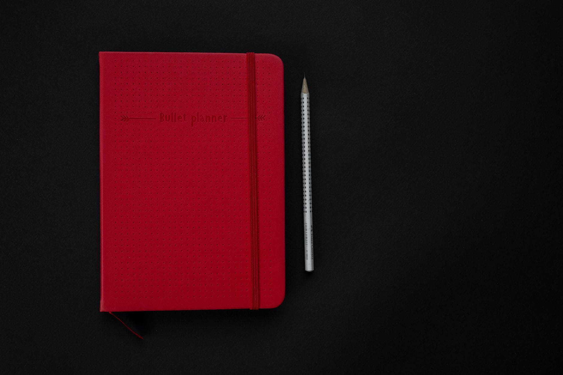 Czerwony bullet journal i ołówek na czarnym tle
