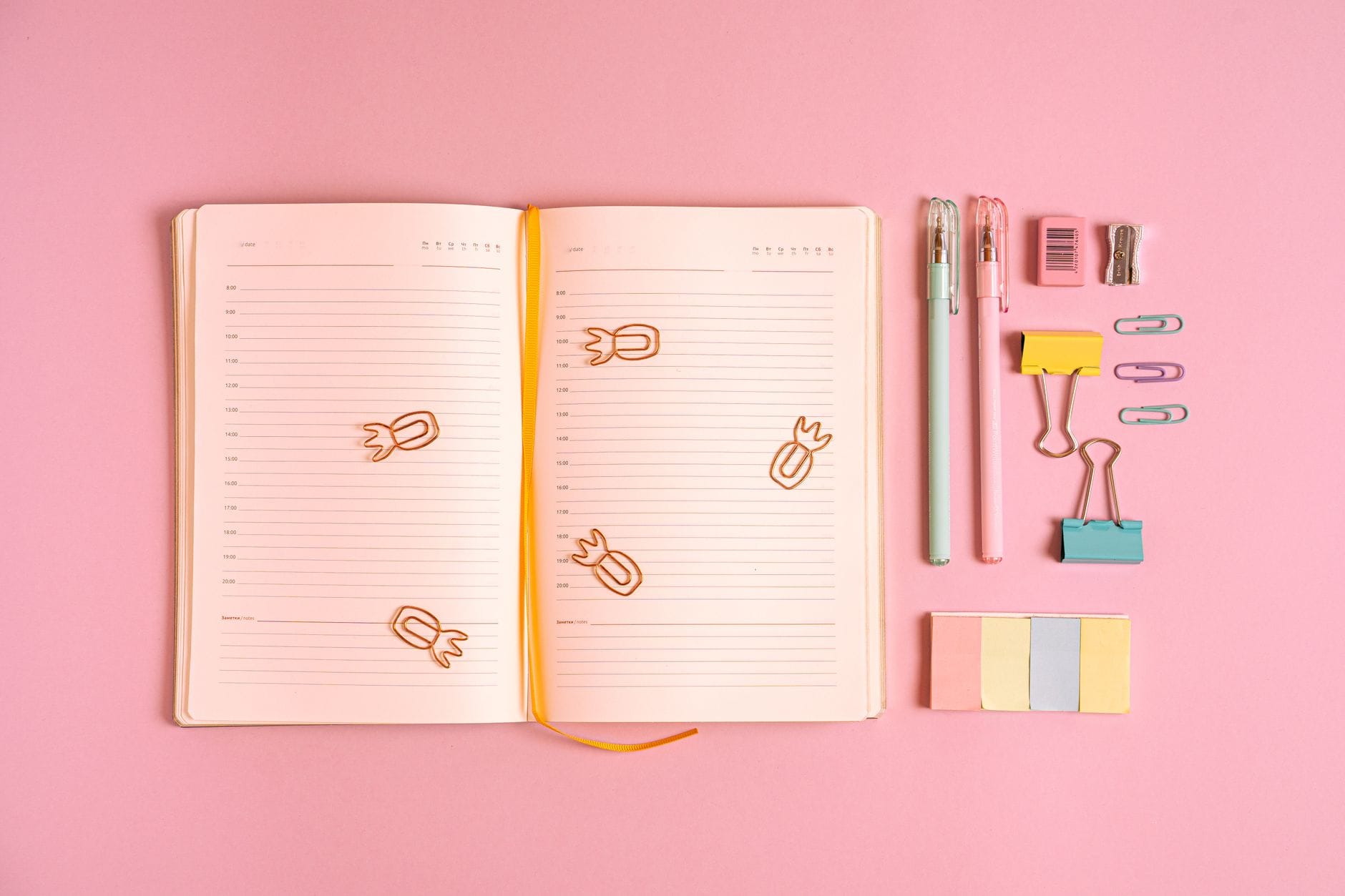 Jak zacząć bullet journal od zera: praktyczny poradnik dla początkujących krok po kroku Kolorowe przybory biurowe i notes na różowym tle jako inspiracja bullet journal